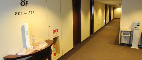 A hotel corridor with a reception desk, a fire extinguisher, and a sign indicating room numbers 801-813.
