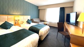 A hotel room with two beds, a desk with a TV, a chair, and a window with curtains.
