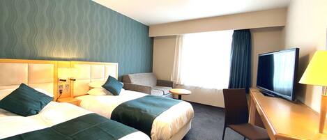 A hotel room with two beds, a desk with a TV, a chair, and a window with curtains.