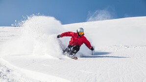 Une personne qui fait du ski sur une pente enneigée.