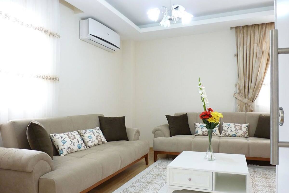 A living room with two beige sofas, a white coffee table, and a vase with flowers.