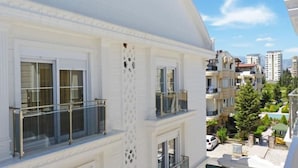 A white building with large windows and balconies, surrounded by other buildings and greenery. - White Star Antalya (Konyaalti)