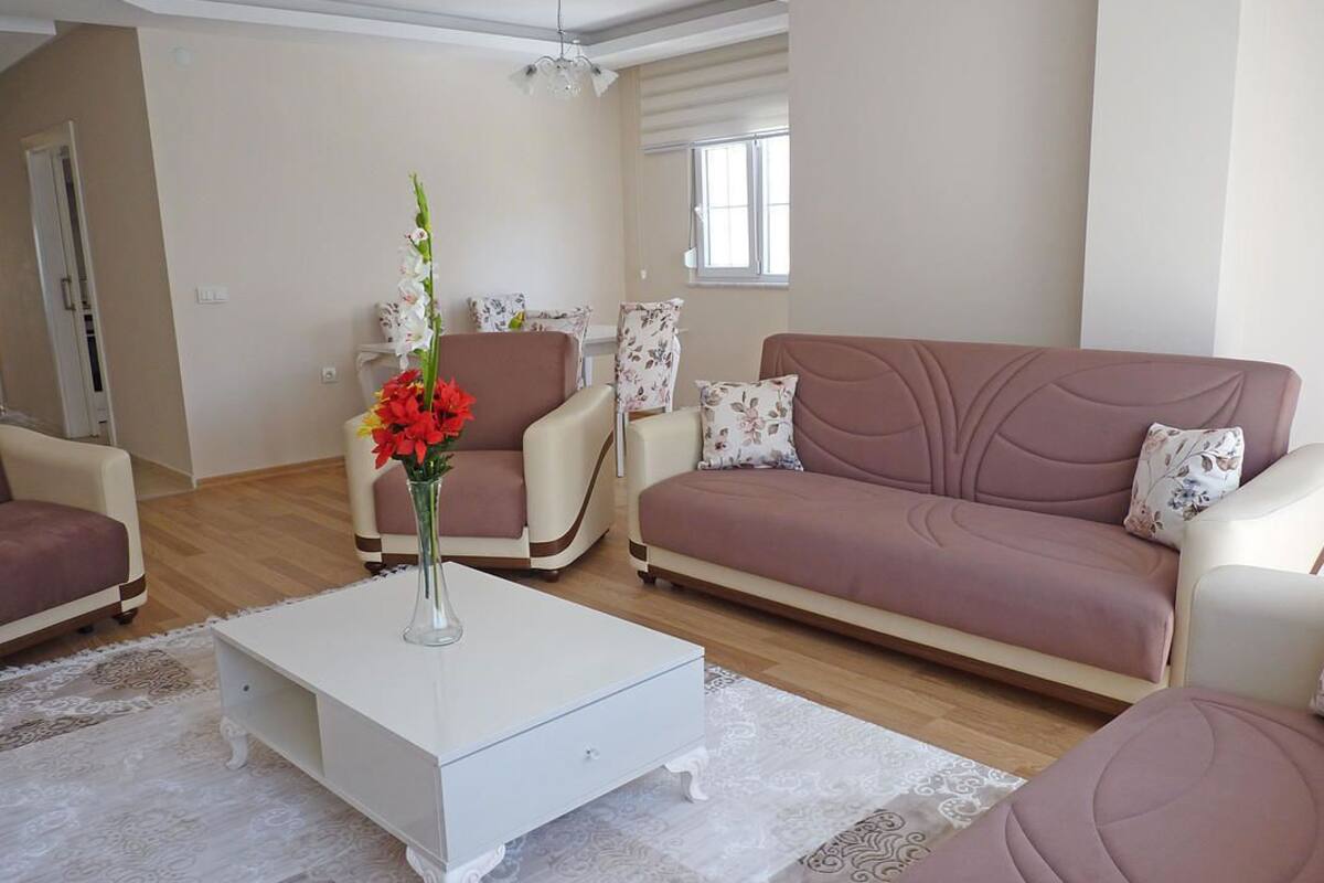 A living room with a white coffee table, a brown sofa, and a chair with floral cushions.