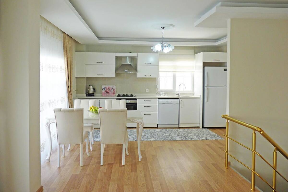 A modern kitchen with white cabinetry, a dining table with chairs, and a small island.