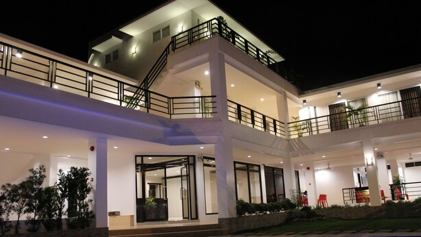 A multi-story hotel with a swimming pool, balconies, and outdoor seating. - Be-ing Suites (Davao)
