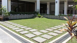 A courtyard with a paved lawn, stone pathway, and potted plants. - Be-ing Suites (Davao)