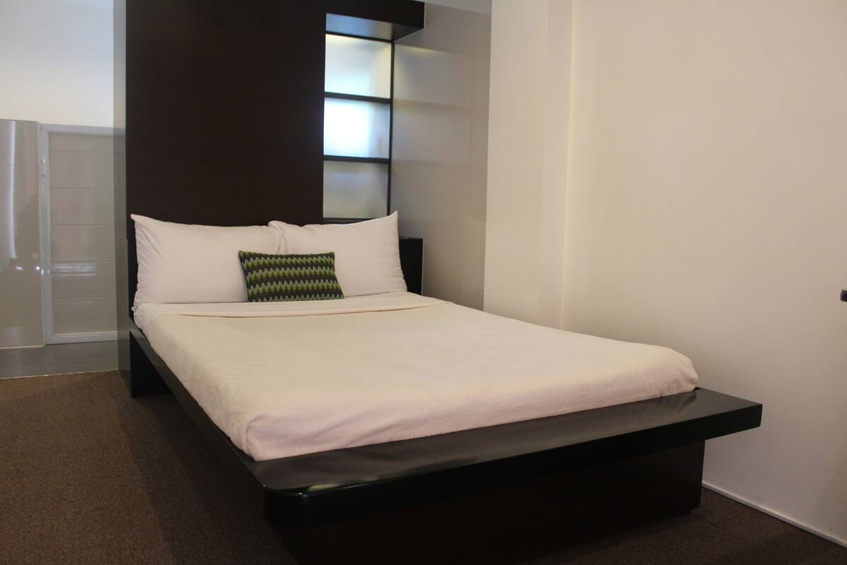 Un dormitorio moderno con cama, mesita de noche y estantería empotrada.