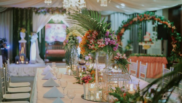 Una larga mesa de banquete con manteles blancos, candelabros y centros de mesa florales.