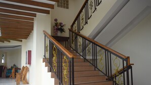 Una escalera con peldaños de madera y barandillas de metal negro con detalles dorados.