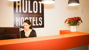 Una mesa de recepción con un letrero que dice "HULOT HOSTELS" y un ordenador portátil encima.