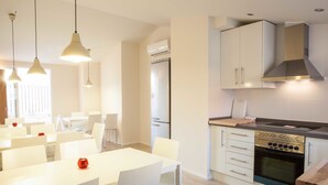 Una cocina moderna con armarios blancos, horno empotrado e iluminación colgante.
