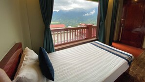 A hotel room with a bed, a view of mountains, and a balcony with a railing. - Botanic Sapa (Sa Pa)