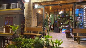 An outdoor seating area with stone walls, wooden benches, and potted plants. - Botanic Sapa (Sa Pa)