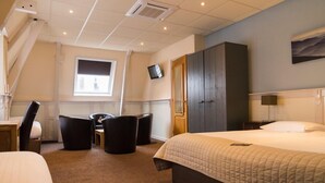 A hotel room with a large bed, a desk with a chair, a TV mounted on the wall, and a wardrobe. - De Gulden Leeuw (Workum)
