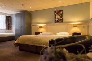 A hotel room with a bed, a nightstand, a chair, and a painting on the wall. - De Gulden Leeuw (Workum)
