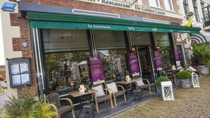 A restaurant with outdoor seating, a green awning, and a sign reading "Hotel - Restaurant De Gulden Leeuw." - De Gulden Leeuw (Workum)