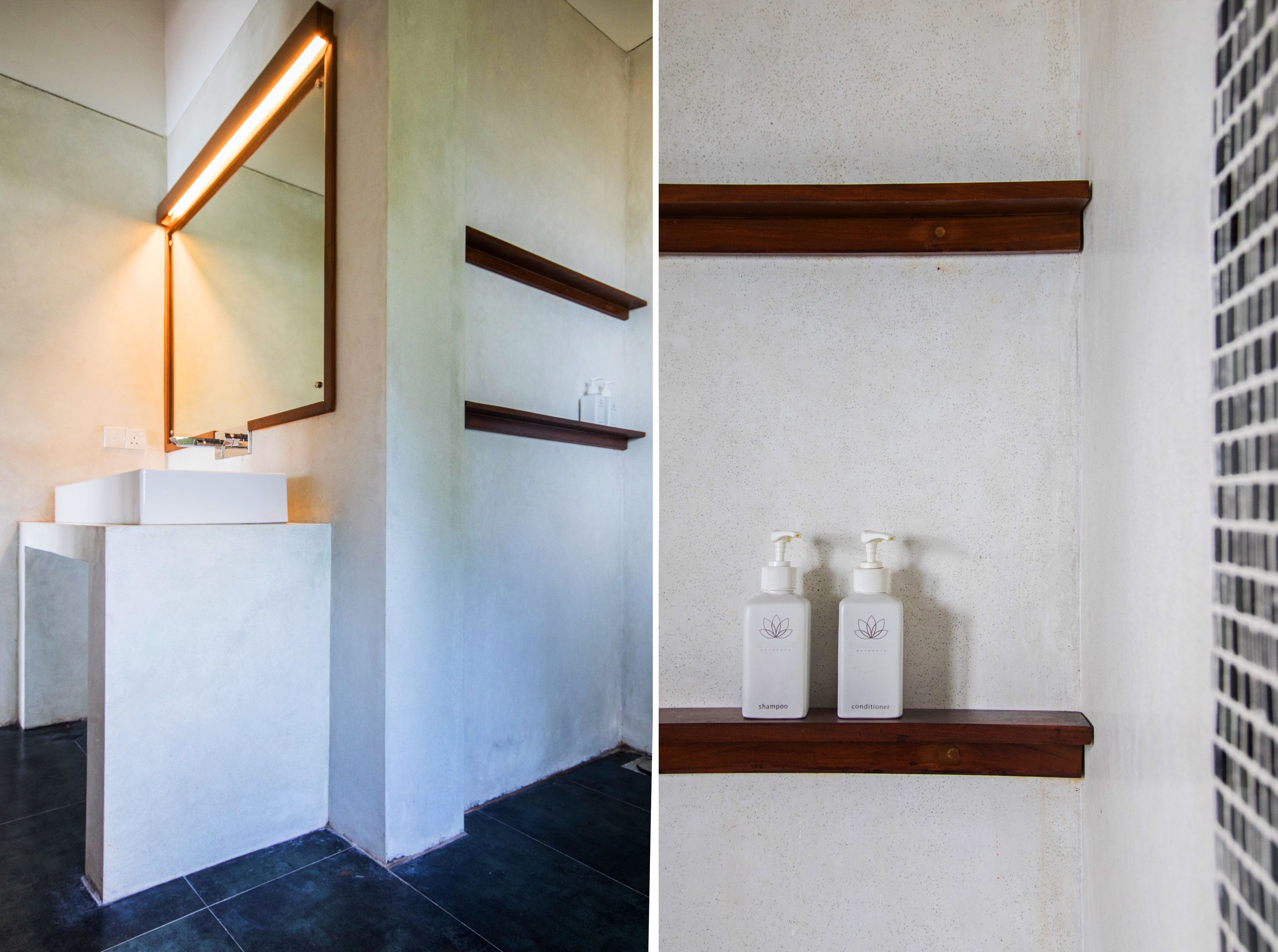 A bathroom with a white sink, a mirror, and two wooden shelves with shampoo and conditioner bottles.