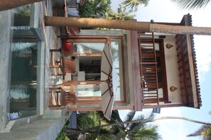A modern building with a pool, wooden deck, and a staircase leading to a balcony. - Skinny Beach House (Unawatuna)