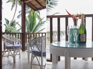 A balcony with wicker chairs and a table, overlooking palm trees and the ocean. - Skinny Beach House (Unawatuna)