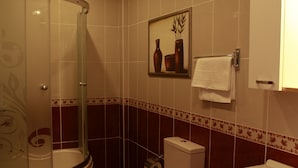 A bathroom with a glass-enclosed shower, a toilet, a sink, and a framed picture on the wall. - Birinci Apart Hotel (Istanbul)