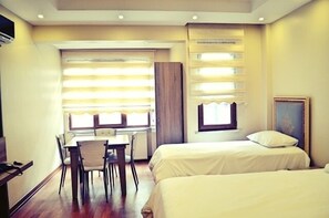 A hotel room with two beds, a dining table with chairs, and a window with blinds. - Birinci Apart Hotel (Istanbul)