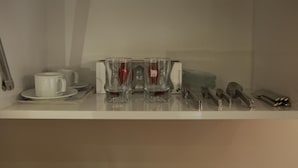 A neatly arranged dining area with a white table set for four, including a white cup, saucer, and four clear glasses with red liquid. Silverware and a knife block are also visible. - Birinci Apart Hotel (Istanbul)