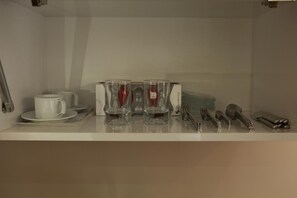 A neatly arranged dining area with a white table set for four, including a white cup, saucer, and four clear glasses with red liquid. Silverware and a knife block are also visible. - Birinci Apart Hotel (Istanbul)