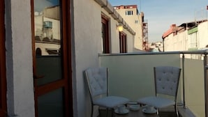 A balcony with two chairs and a small table, overlooking a street with buildings. - Birinci Apart Hotel (Istanbul)