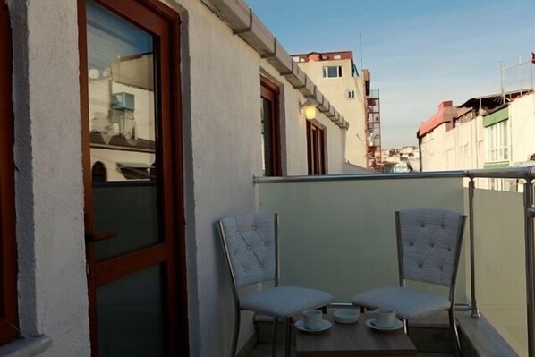 A balcony with two chairs and a small table, overlooking a street with buildings. - Birinci Apart Hotel (Istanbul)
