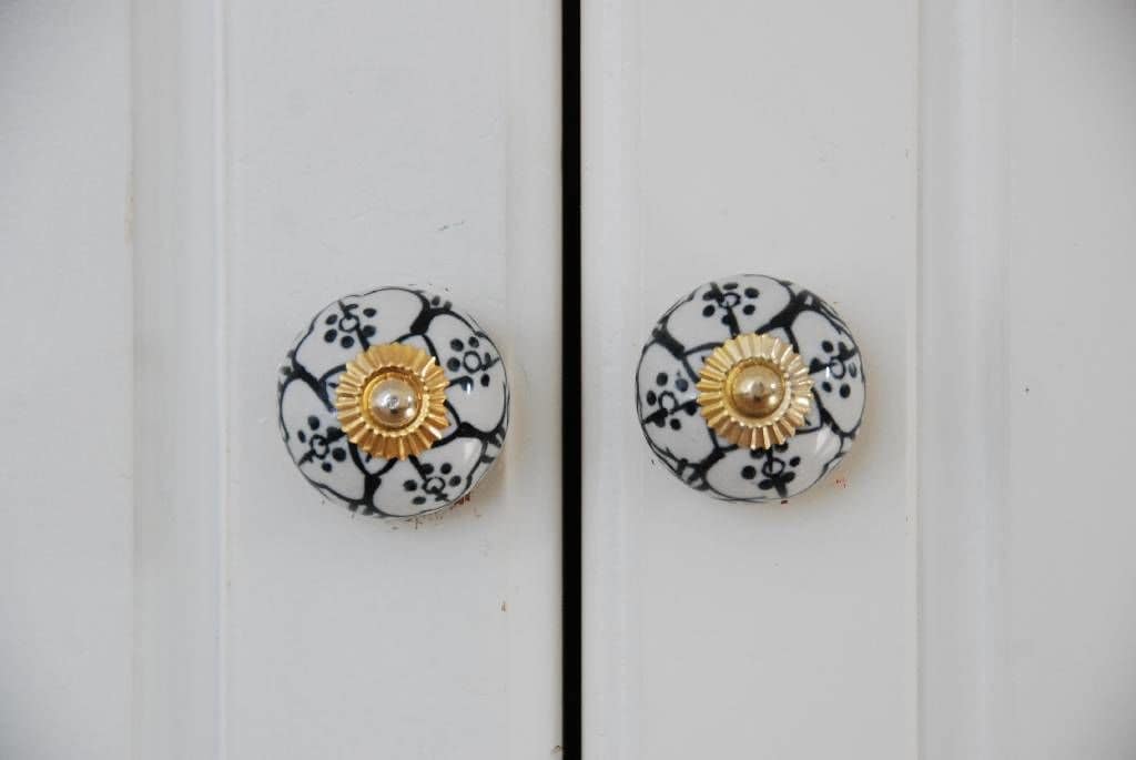 Dos pomos de puerta redondos con un motivo floral y un diseño dorado en el centro.