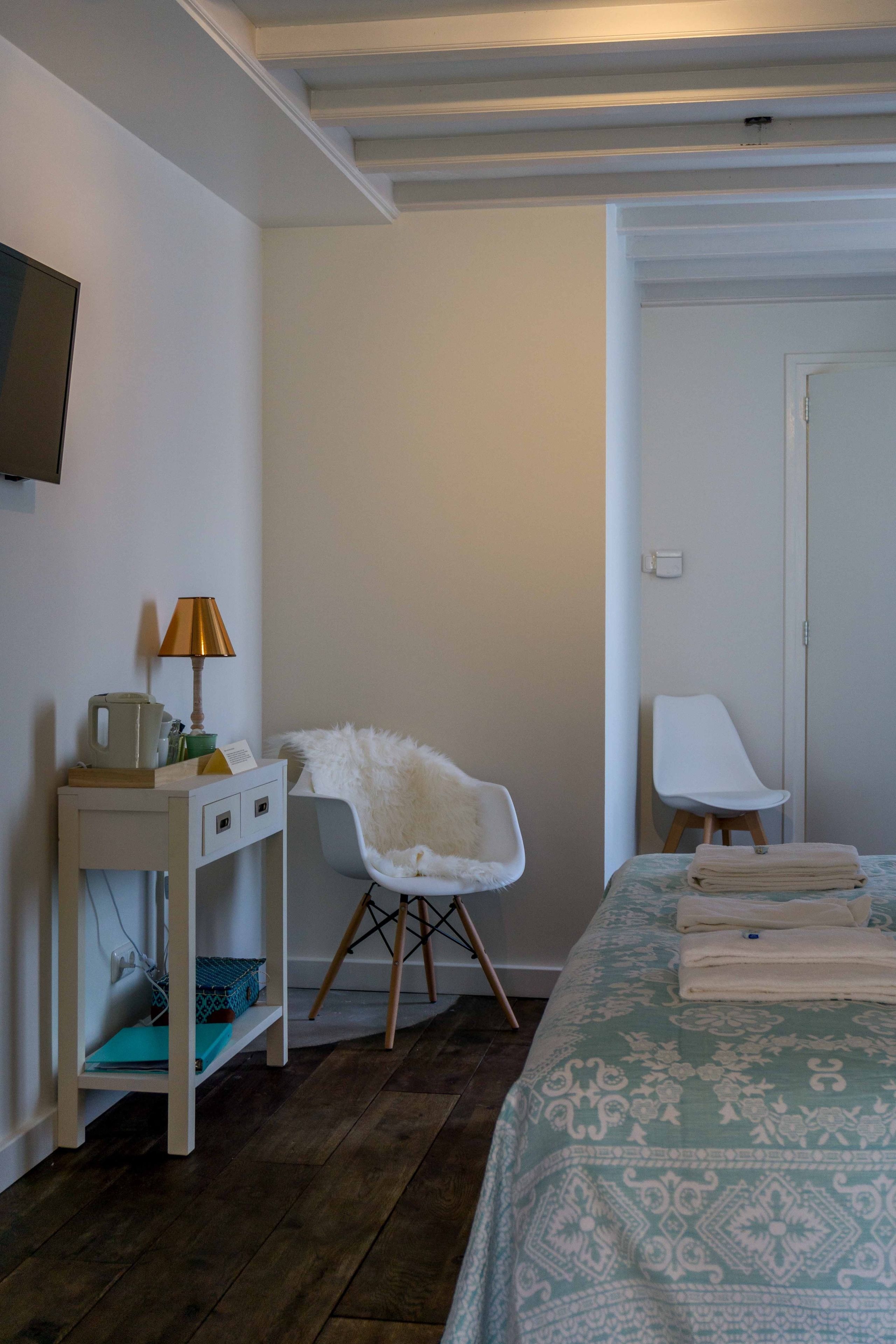 A bedroom with a bed, a bedside table with a lamp, a chair, and a wardrobe.