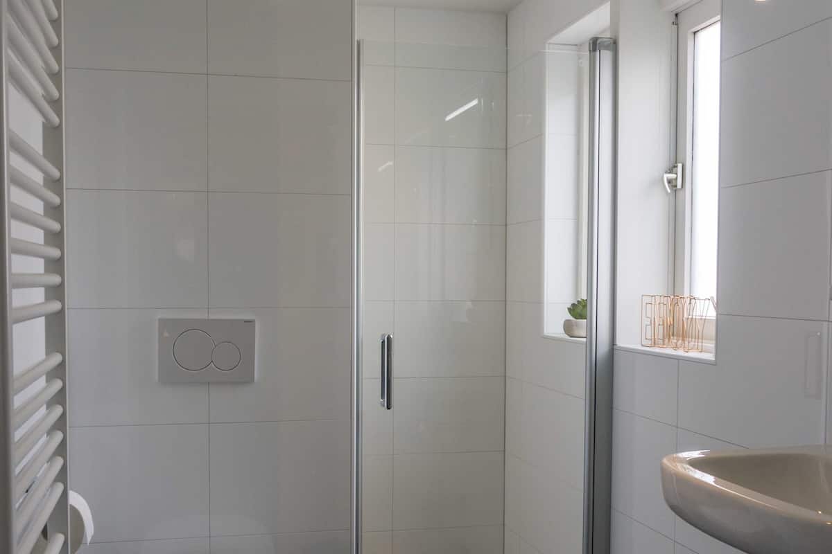 Een moderne badkamer met toilet, douche en wastafel.
