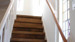 Eine Holztreppe mit weißen Geländern und einem Fenster mit Gittermuster.