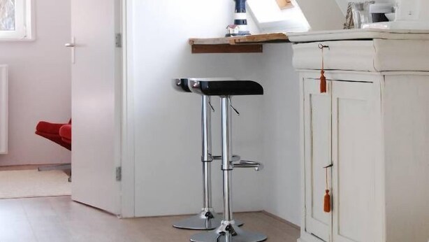 A kitchen with a sloped ceiling, a wooden countertop, a white cabinet, and a black bar stool. - Duinlust Dishoek (Koudekerke)