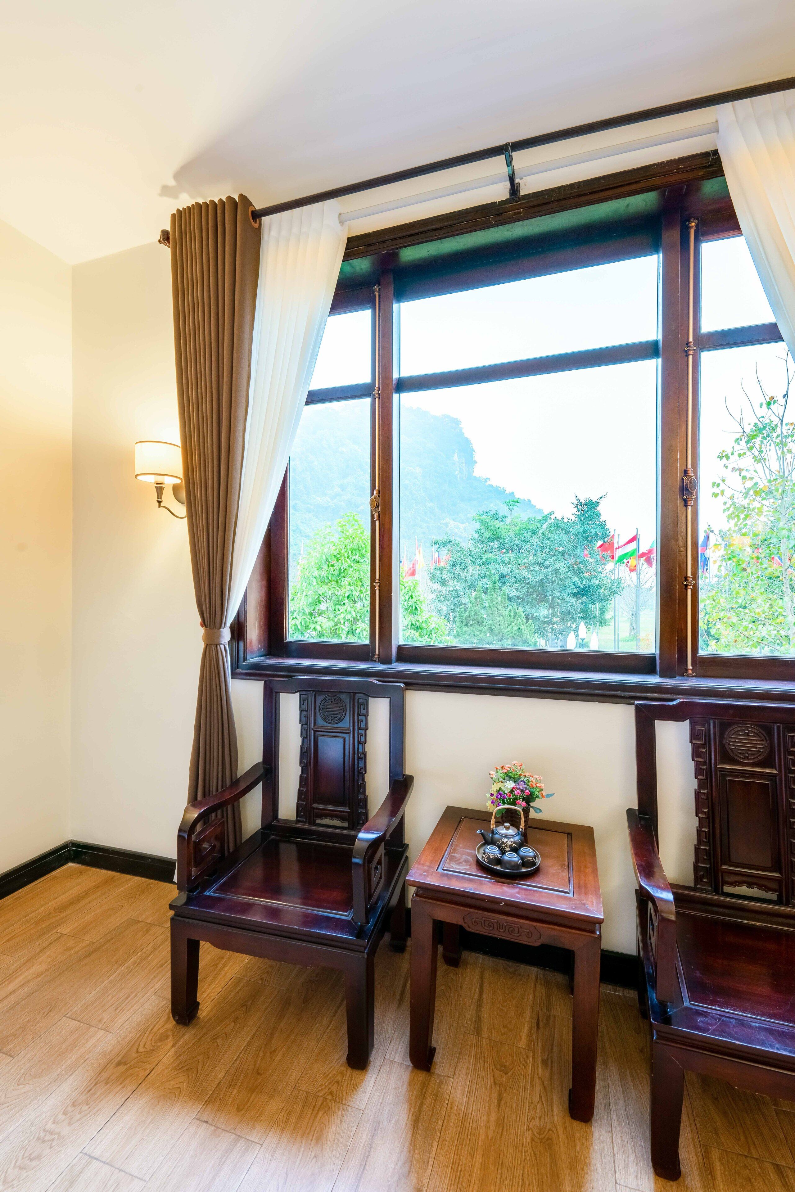 A room with two wooden chairs, a small table with a decorative item, and a window with curtains.