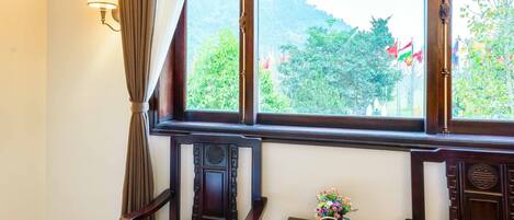 A room with two wooden chairs, a small table with a decorative item, and a window with curtains.