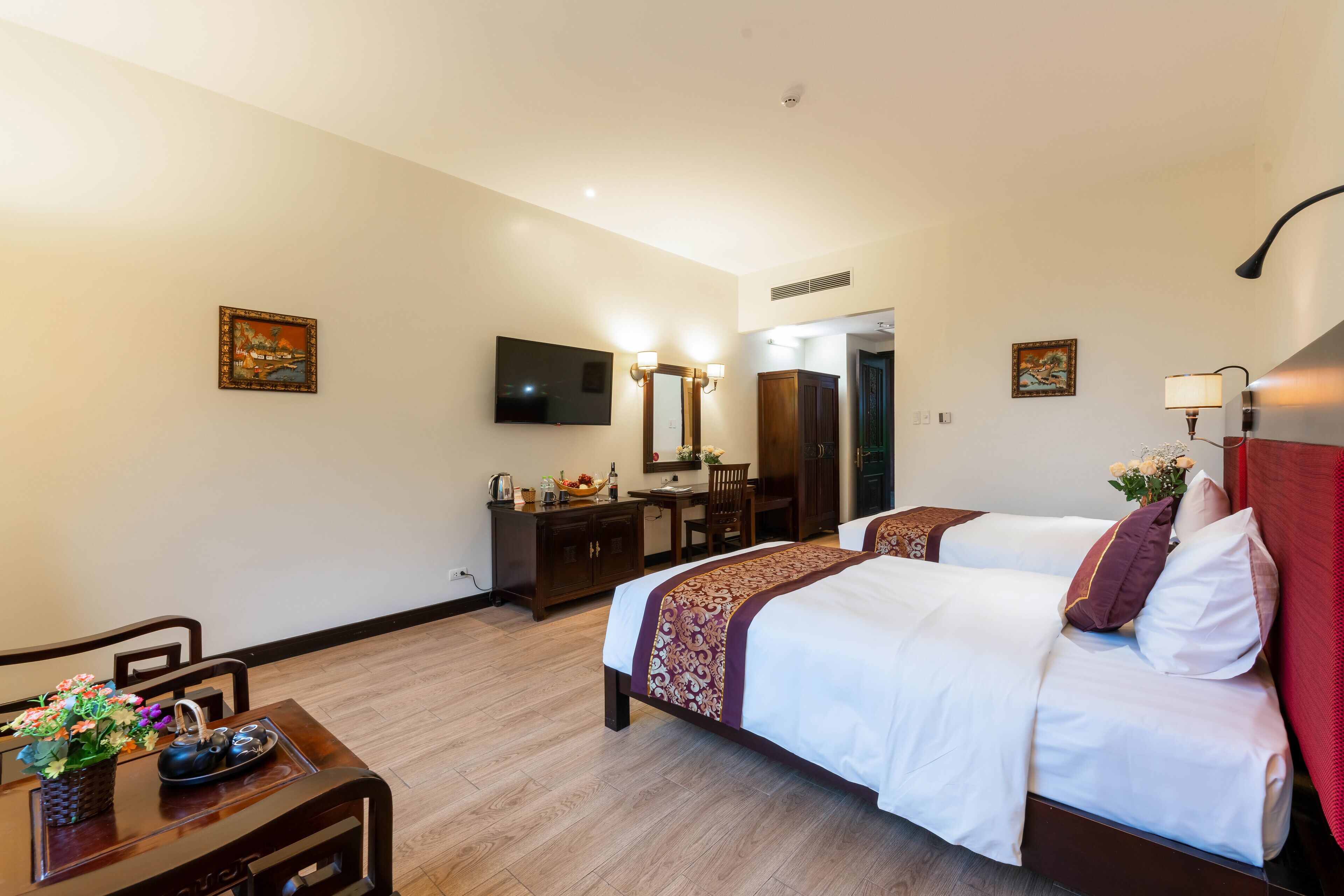 A hotel room with two beds, a desk, a TV, and a bathroom visible through an open door.