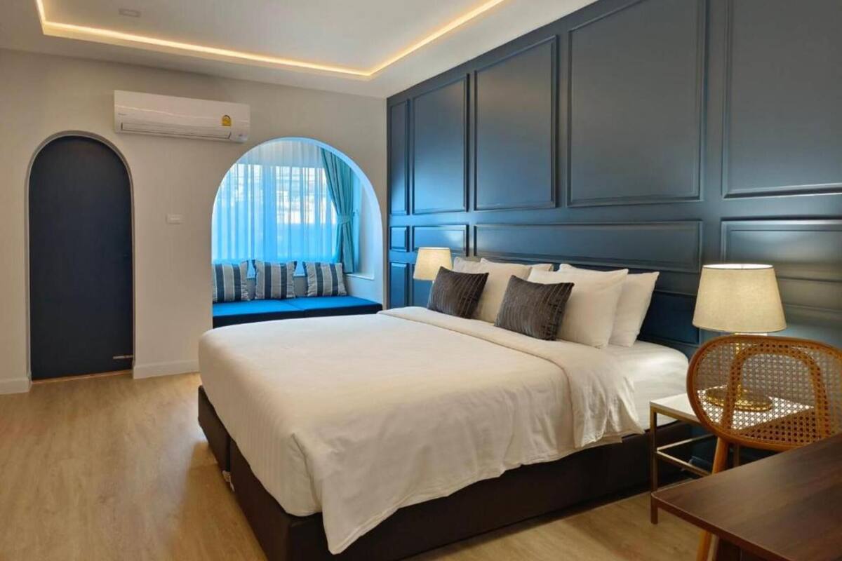 A modern hotel room with a large bed, a seating area with a view, and a dining table.