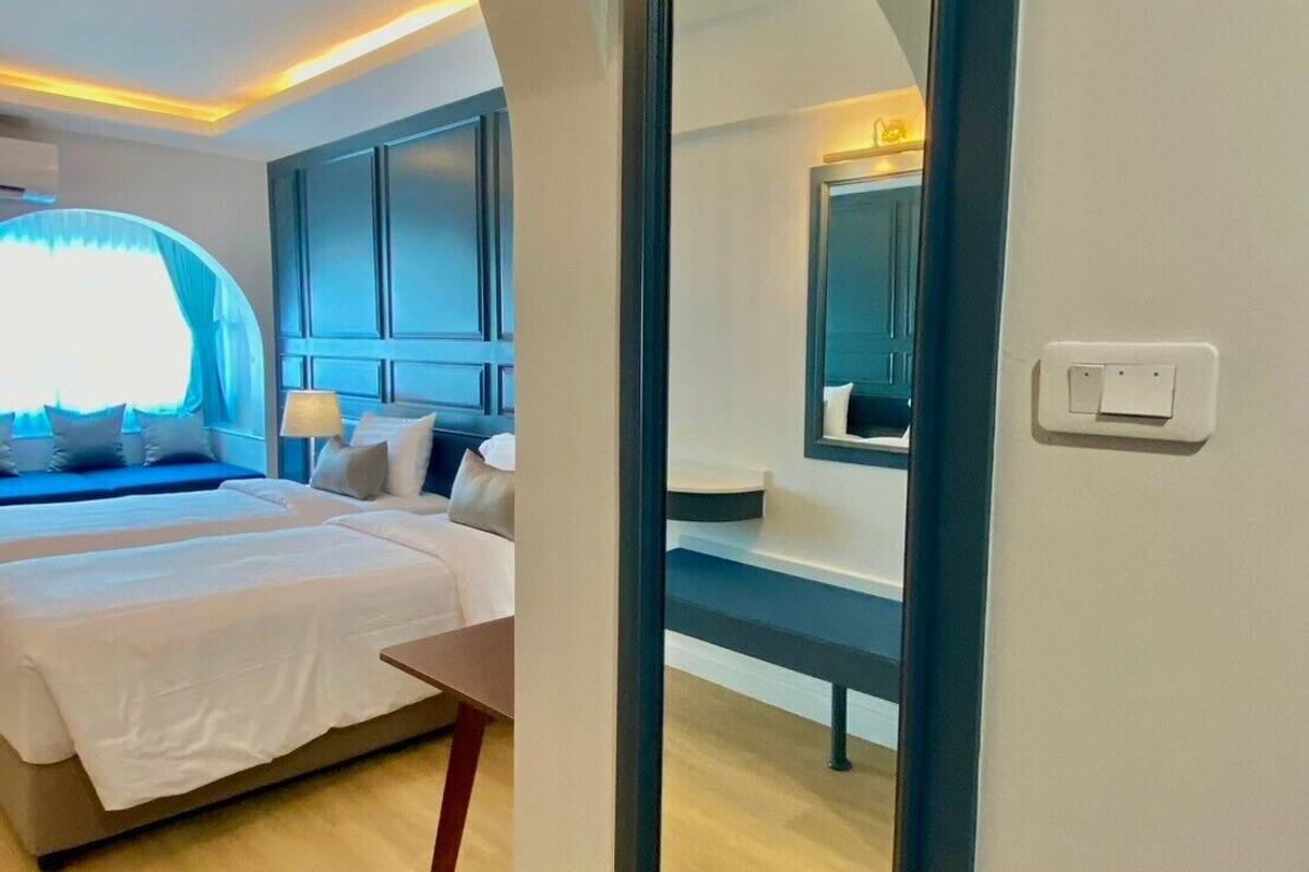 A modern hotel room with a large bed, a desk, and a mirror.