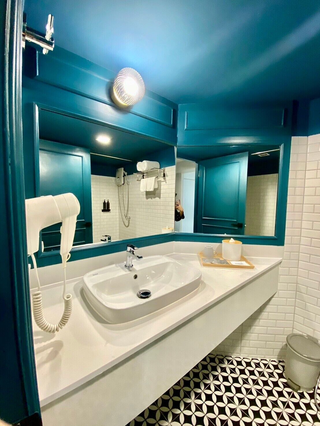 A bathroom with a white sink, a hairdryer, and a mirror.