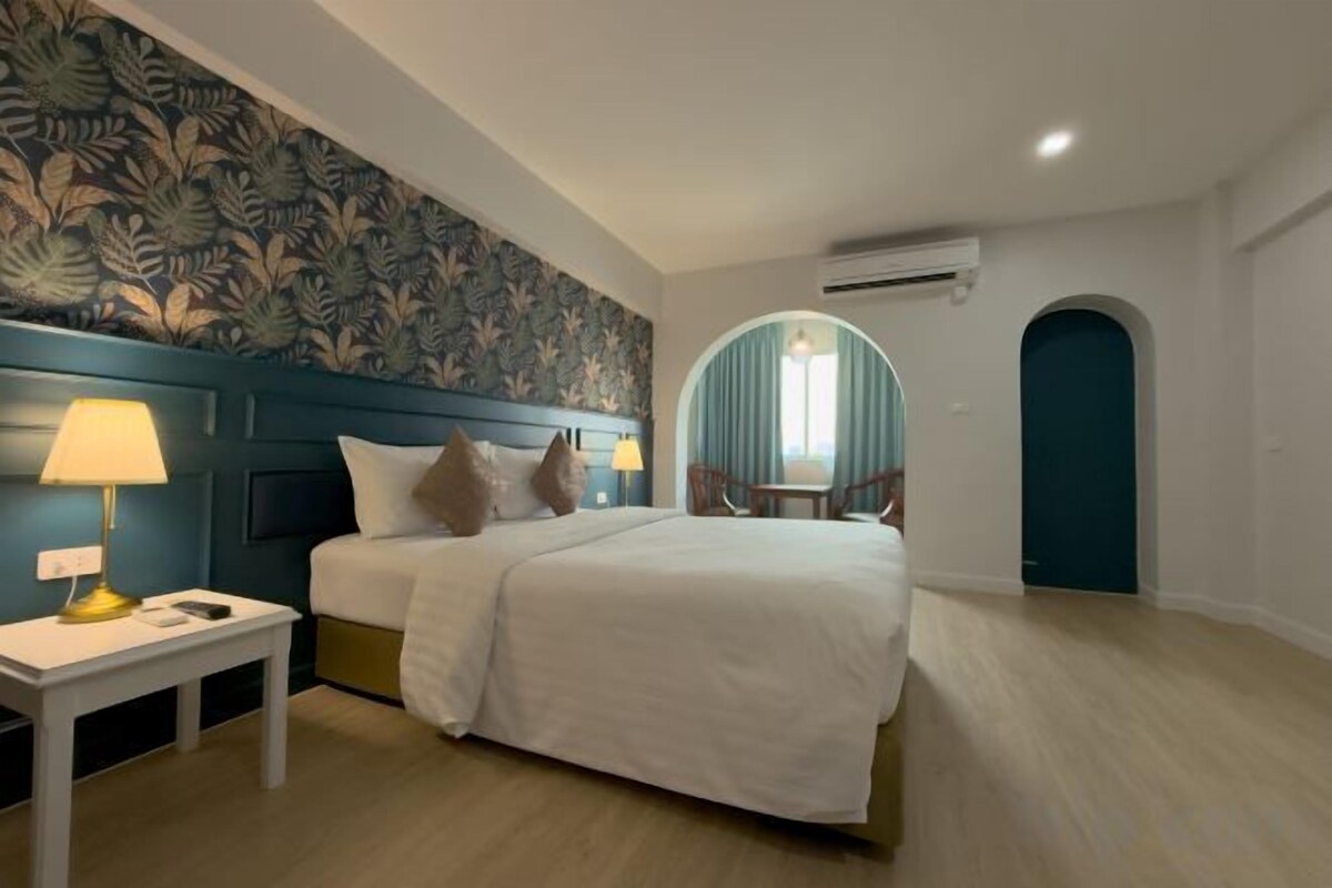 A hotel room with a bed, bedside tables, a chair, and a window.