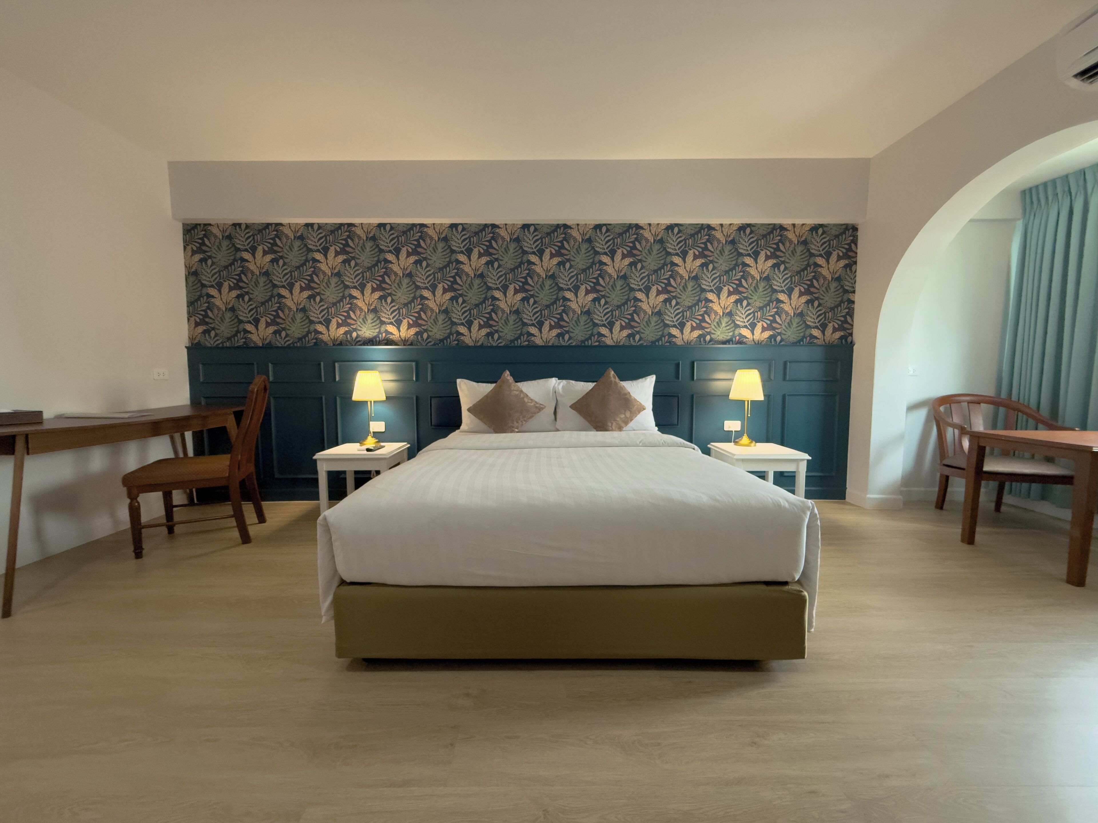 Habitació d'hotel amb un llit gran, dues taules de nit amb llums, un escriptori i una cadira.