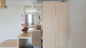 A modern room with a wooden desk, a chair, and a small table with a vase of flowers. - Regent Ngamwongwan (Nonthaburi)