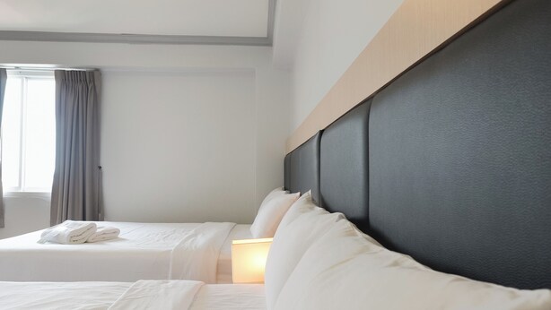 A hotel room with two beds, a headboard, and a window with curtains. - Regent Ngamwongwan (Nonthaburi)