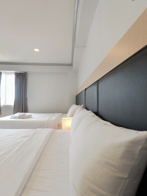 A hotel room with two beds, a headboard, and a window with curtains. - Regent Ngamwongwan (Nonthaburi)