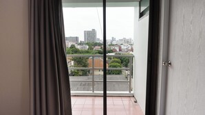 A balcony with a city view, a sliding glass door, and a metal railing. - Regent Ngamwongwan (Nonthaburi)