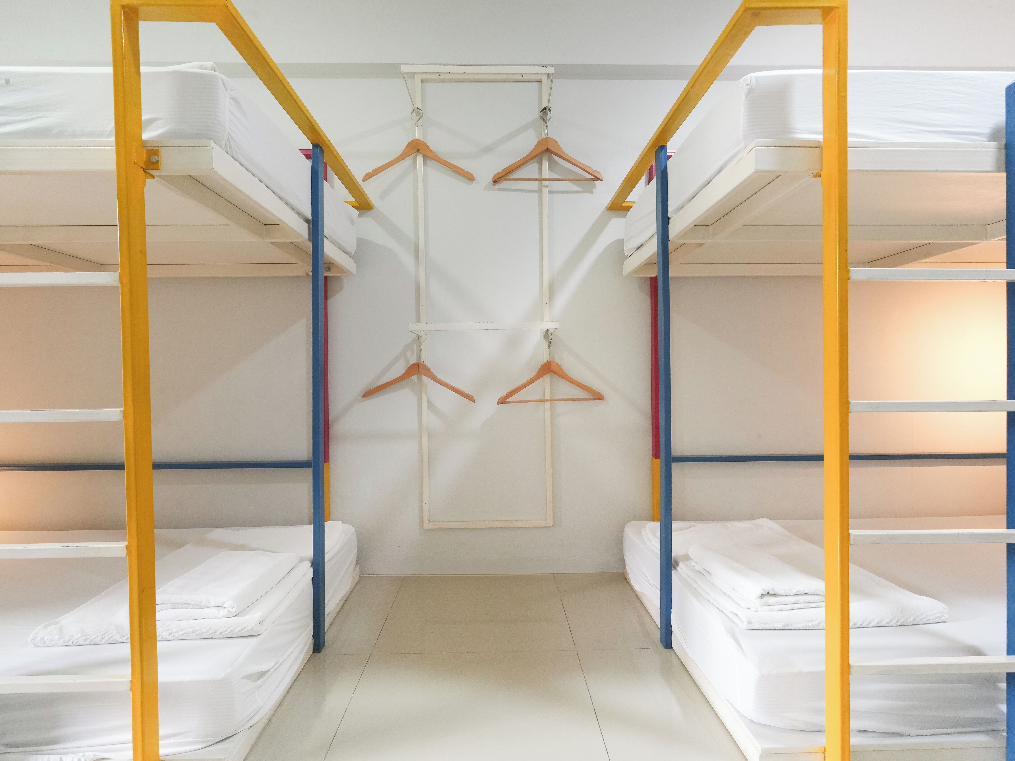 A bunk bed room with a central hanging rack and a white wall.