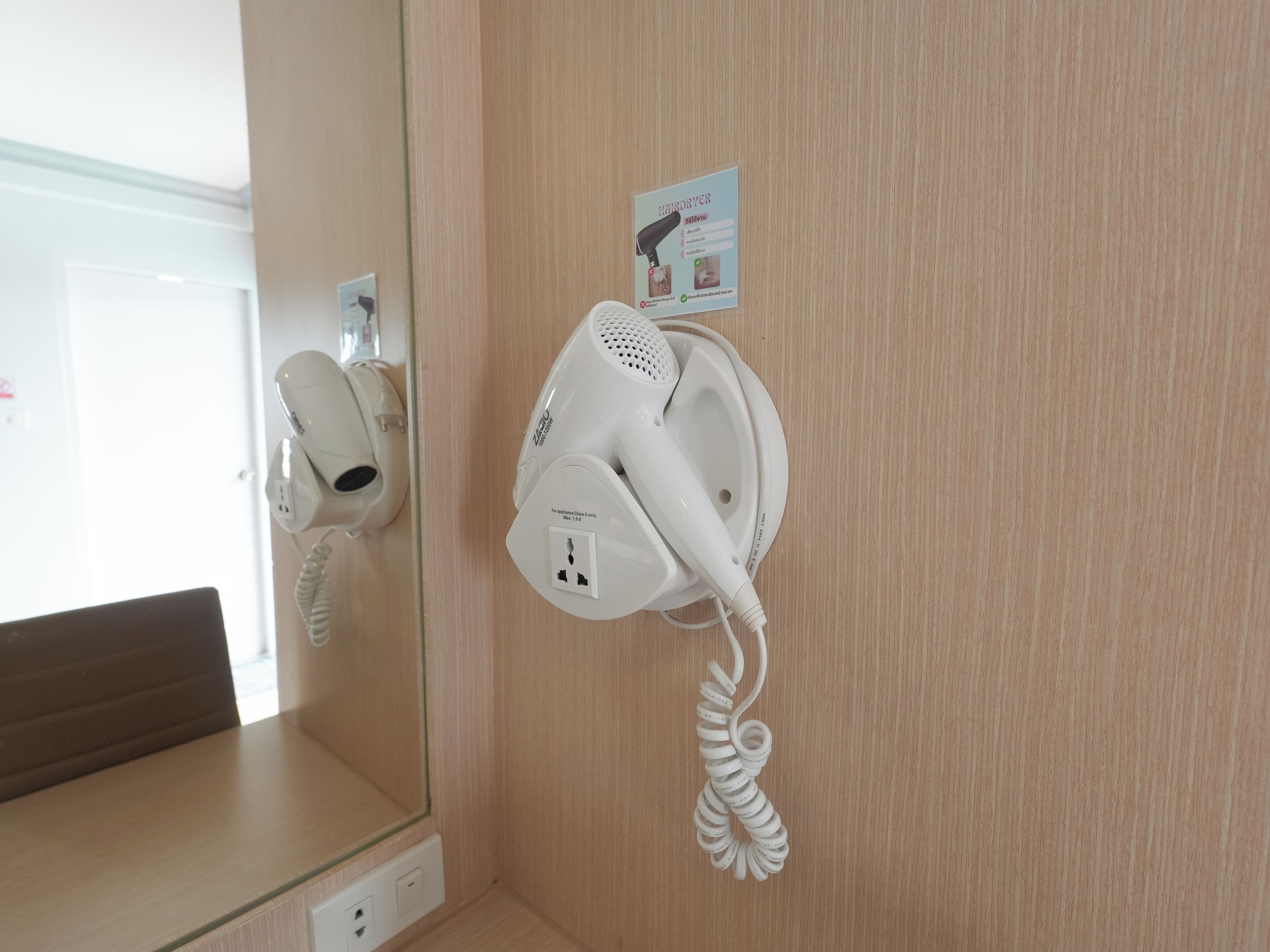 A hairdryer and phone on a wall in a hotel room.