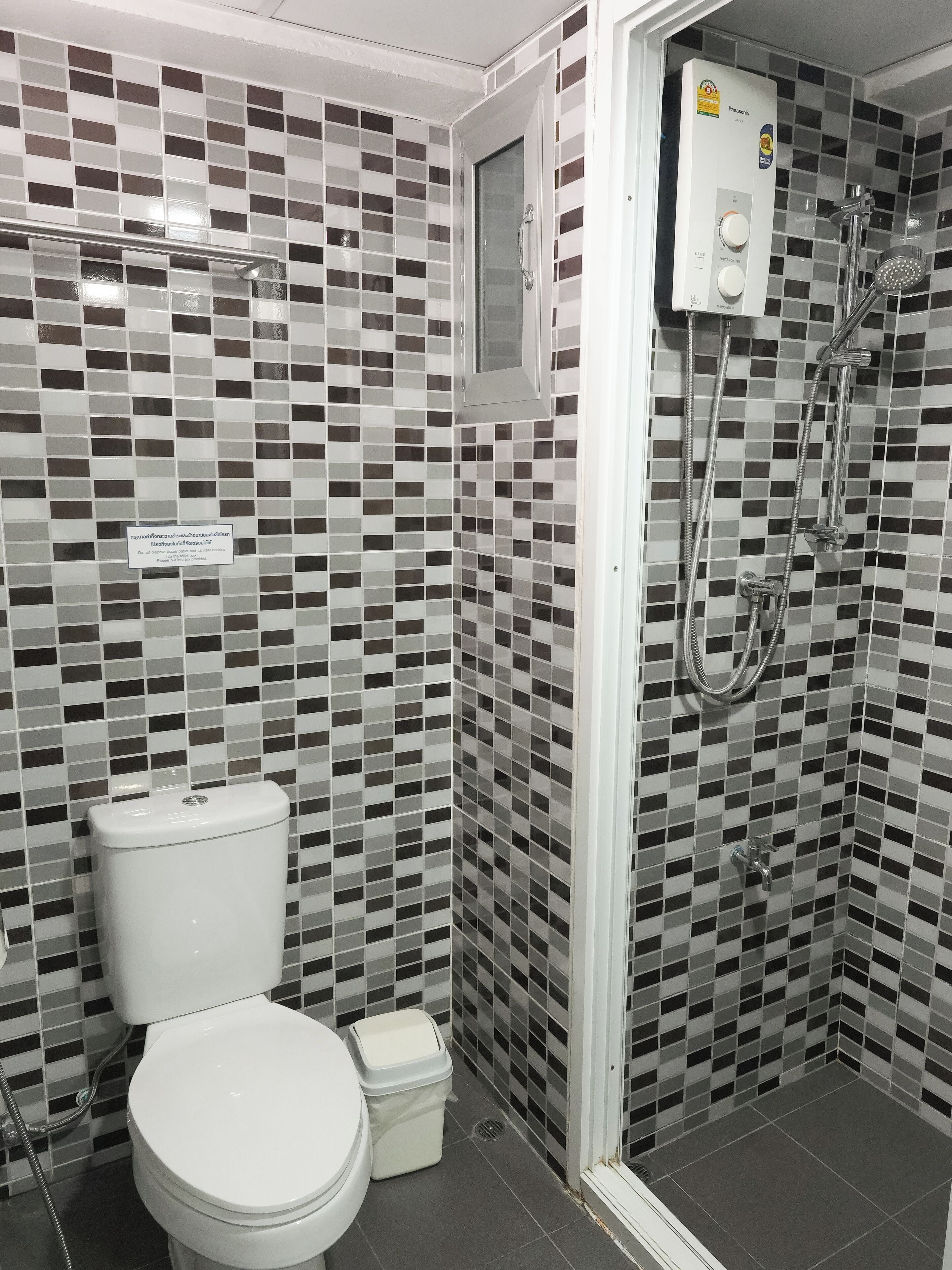 Un baño con inodoro, bidé y ducha con panel de control.