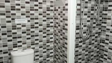 Un baño con inodoro, bidé y ducha con panel de control.